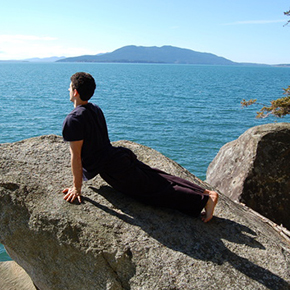 椎間板ヘルニア｜岩の上でうつ伏せから上体を反らすポーズをとっている男性